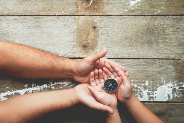 planning future directions for children Father and daughter hands holding compass on dark wooden background top view copy space. Future direction concept Navigating Challenges with family stock pictures, royalty-free photos & images