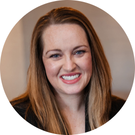 Headshot of Jacki Brown, Fractional Marketing Leader for Hospitality & Travel Tech, a woman with long brown hair and a bright smile, wearing a dark top against a neutral background.