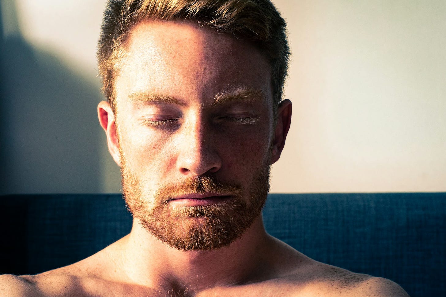 Headshot of young man with beard meditating.