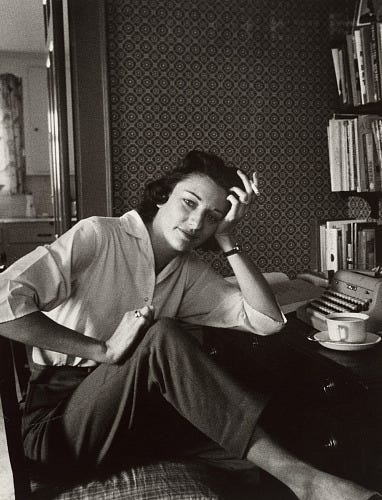 Sepia photograph of Anne Sexton at her desk with a typewriter and tea cup and bookshelves