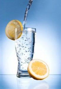 a glass of water with a lemon on the glass.