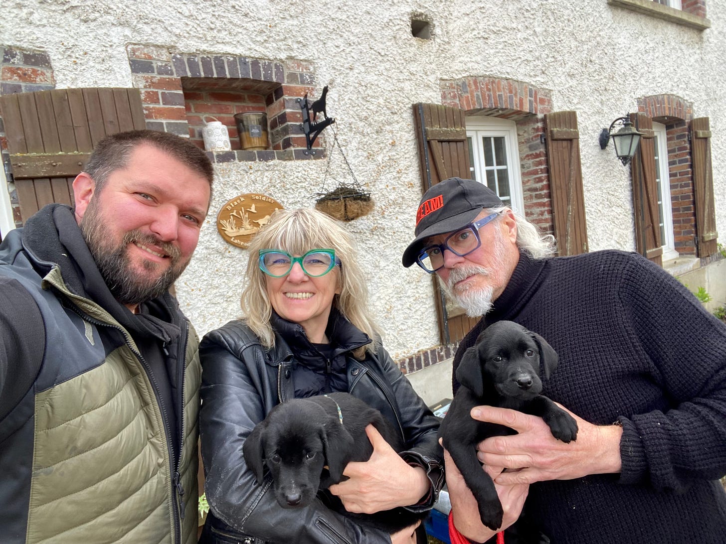 Three people and two labrador puppies