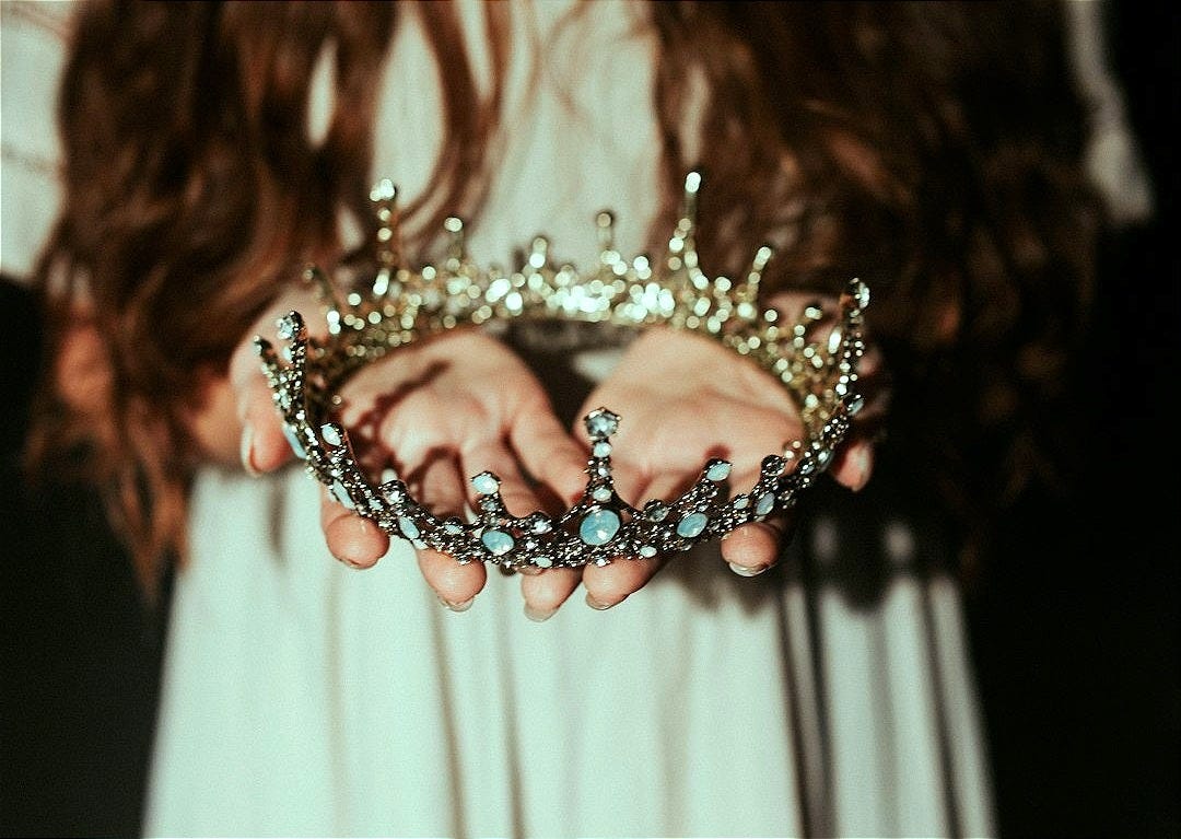 woman holding silver-colored crown