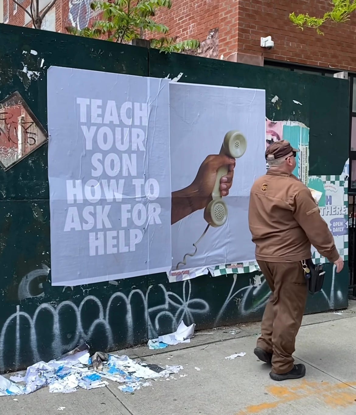 A sinistra la scritta "Teach your son how to ask for help" e di fianco una mano che regge un telefono