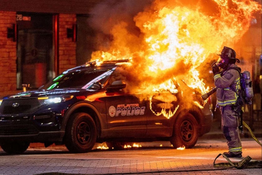 Atlanta firefighters prepared to extinguish a police car that was set afire during a Forest Defenders protest in Atlanta, on Jan 21, 2023.