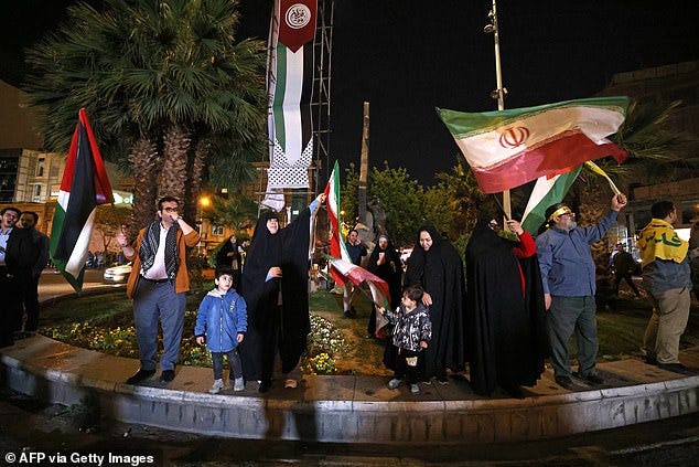 Demonstrators wave Iran's flag and Palestinian flags as they gather at Palestine Square in Tehran on April 14, 2024