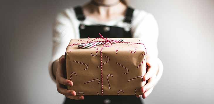 Photo of a woman holding out a wrapped present.