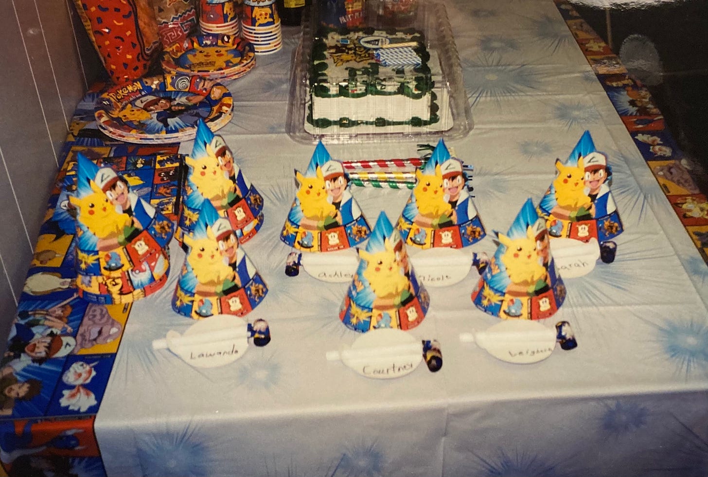 The table was covered with Pokémon-themed hats, plates, party blowers, cups, and a decorated cake