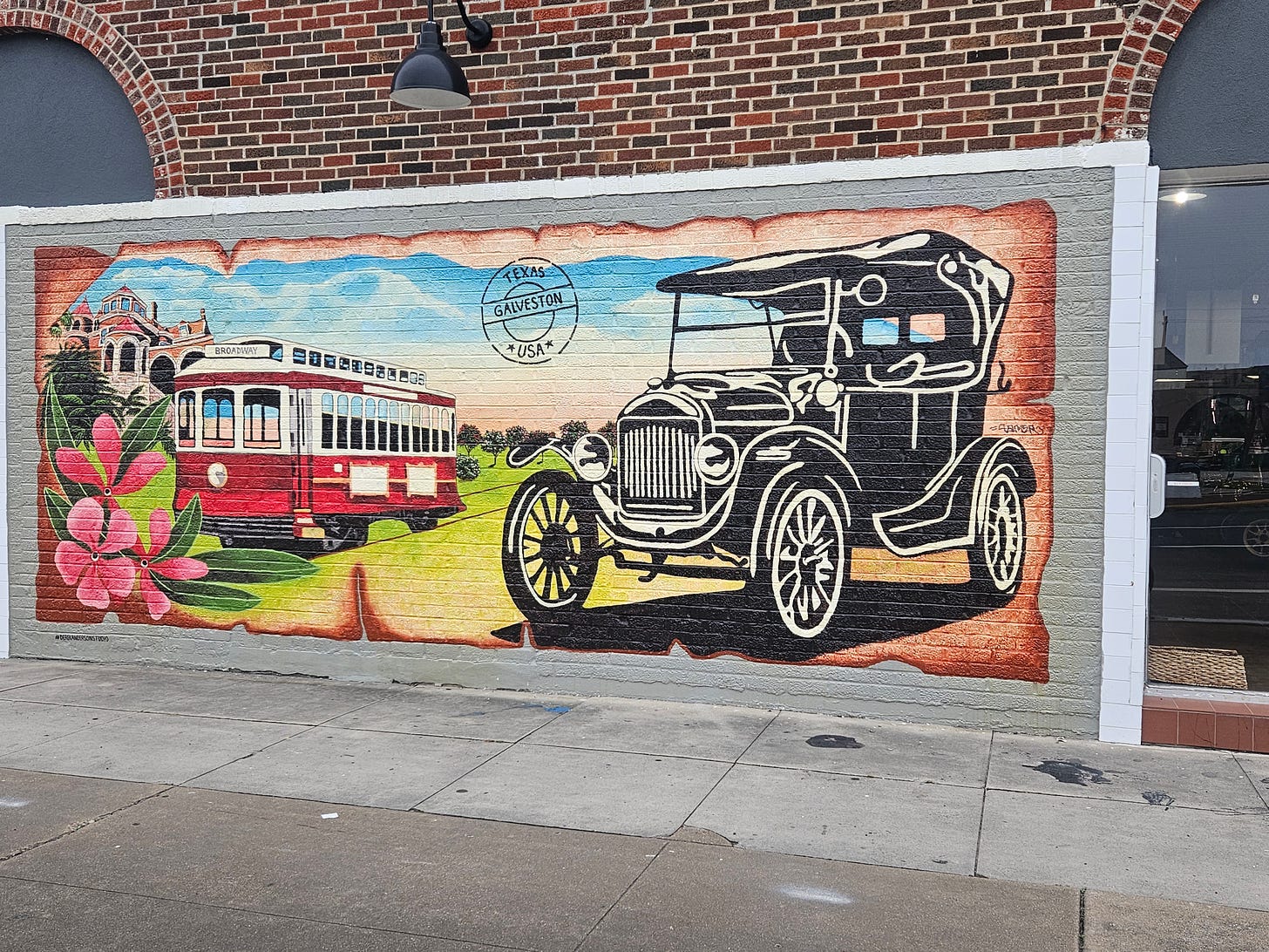 A painted wall mural in Galveston showing and old car and the town trolley