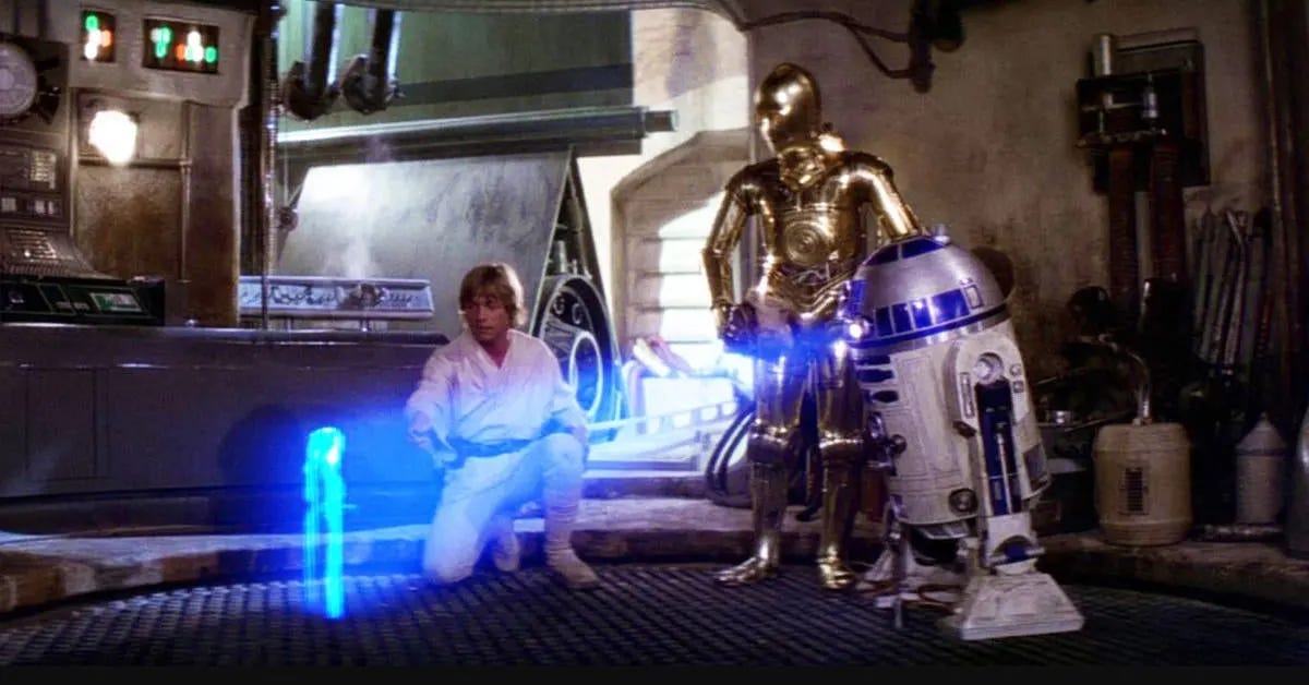 R2-D2 projects a hologram of Princess Leia as Luke Skywalker and C-3PO look on.