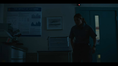 Screenshot from Awake 2021, showing room with posters on right, as Gina Rodriguez opens door.
