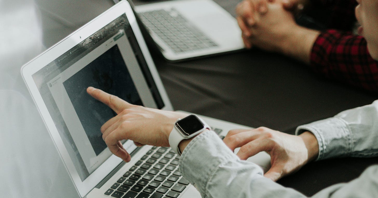 two people sitting at a table with laptops