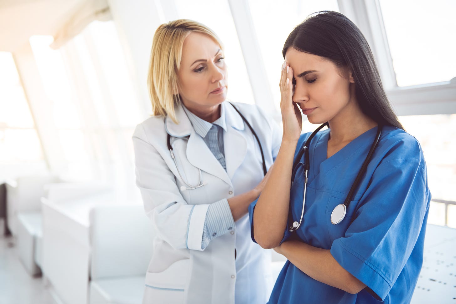 burned out young nurse being consoled by older colleague