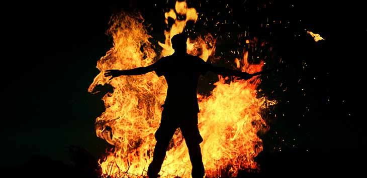 Photo of the sillhouette of a man in front of a bonfire.