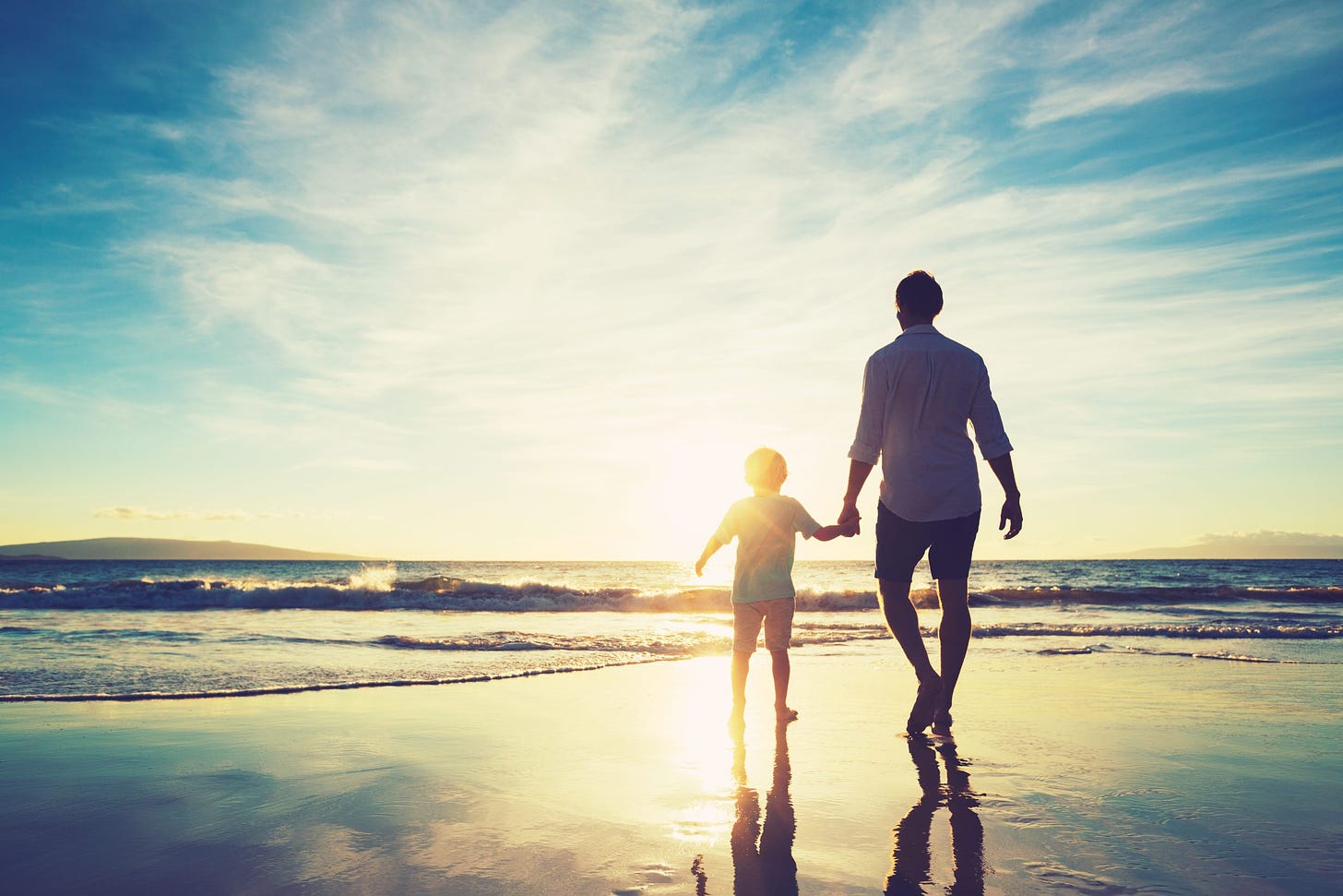 Father,And,Son,Holding,Hands,Walking,Together,On,The,Beach