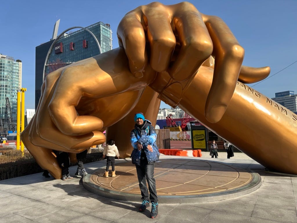 A person holding a child in front of a large statue

Description automatically generated