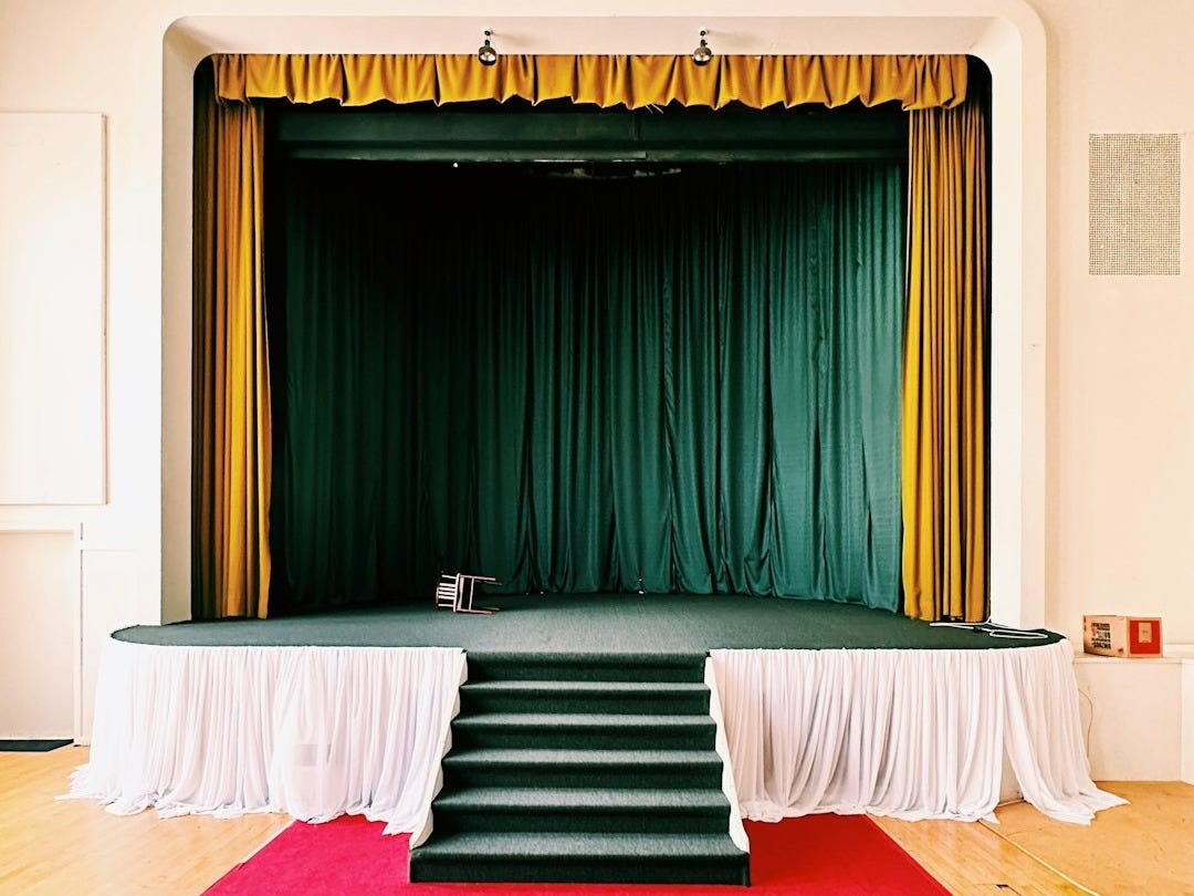 a stage with a red carpet and a green curtain