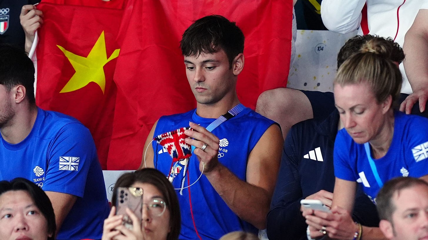 Great Britain's Tom Daley knitting as he watches the Women's Synchronised 3m Springboard Final at the Aquatics Centre on...