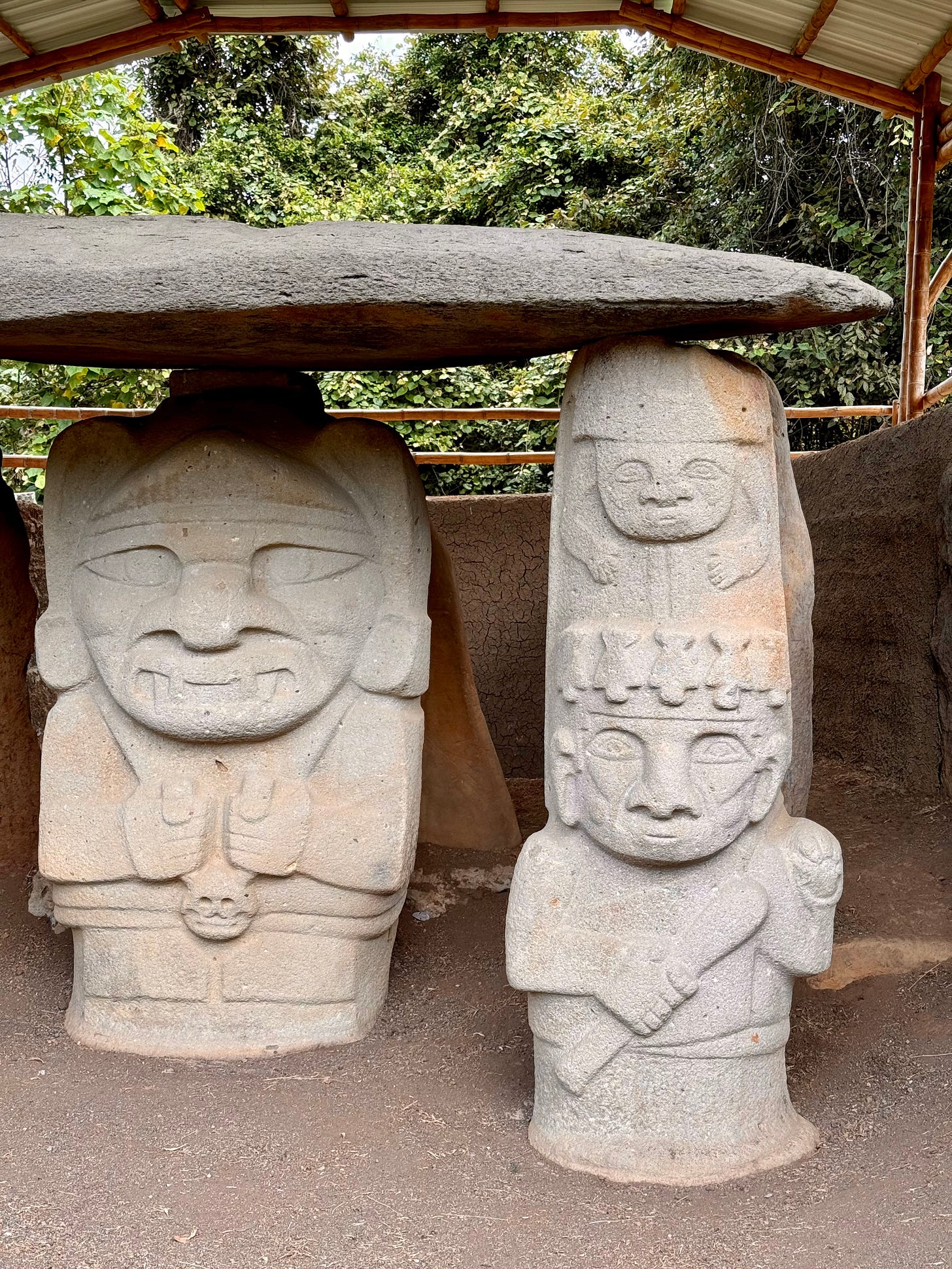 Dos esculturas funerarias en San Agustín. La de la izquierda es el personaje principal y parece llevar al cuello un collar con la cabeza de un enemigo. La otra parece ser un guardián que tiene en su cabeza una figura antropomorfa. Foto propia.