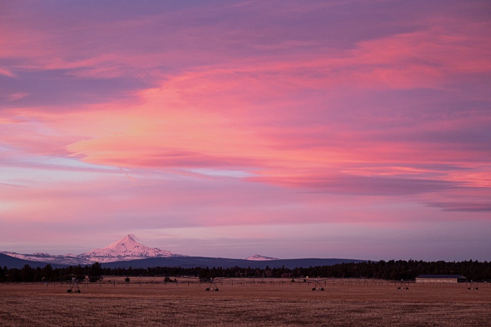 Clouds from a dramatic pink and blue sunset hover over Mt. Jefferson, looking to the west from Sisters, Oregon. 