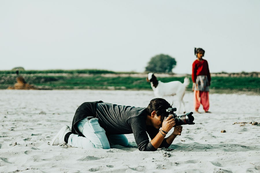 Photographer kneeling on beach taking out a photograph.