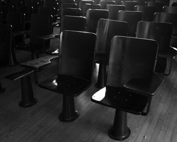 A black-and-white photo shows rows of chairs in a classroom.