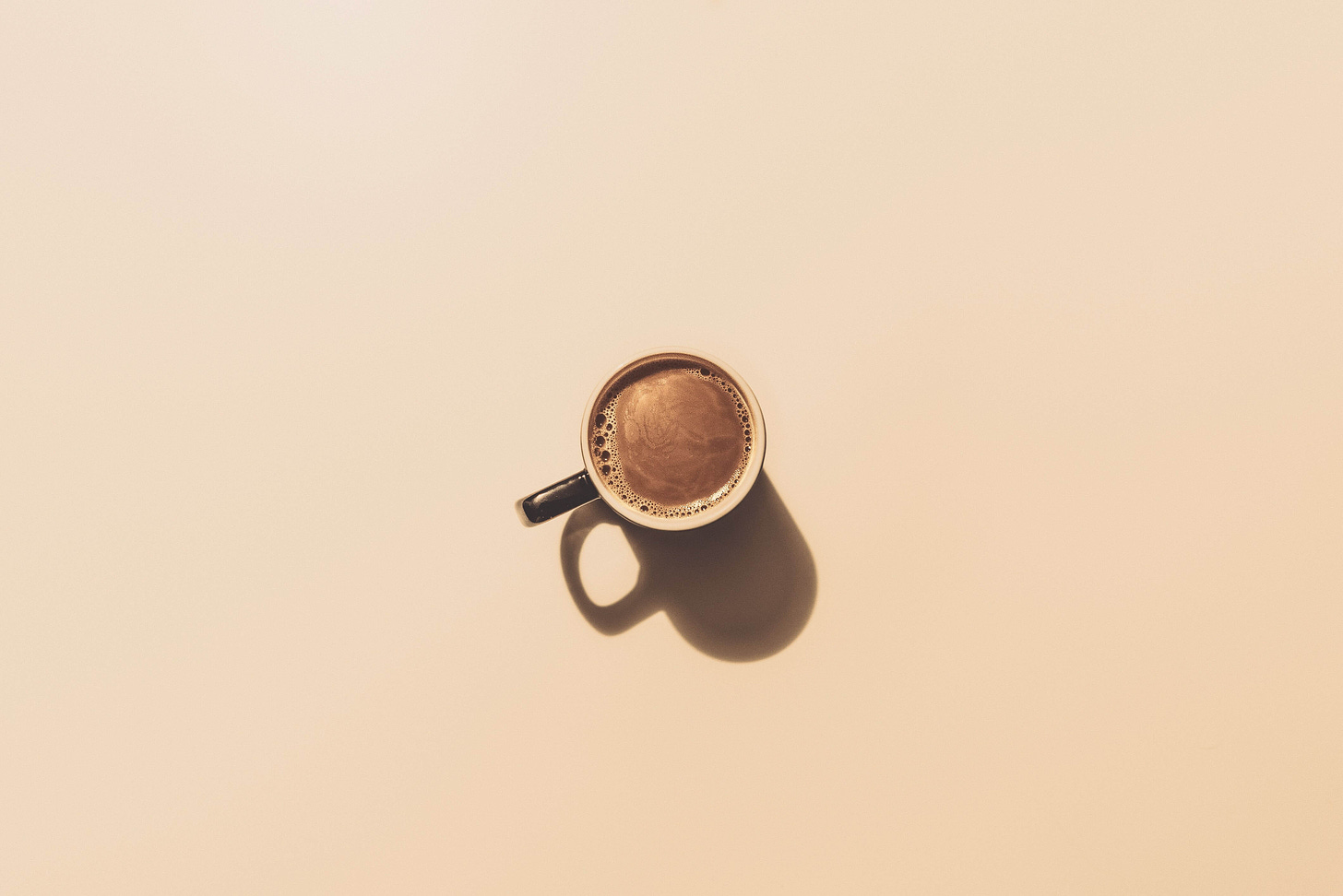 above shot of small peach colored coffee mug on a peach background