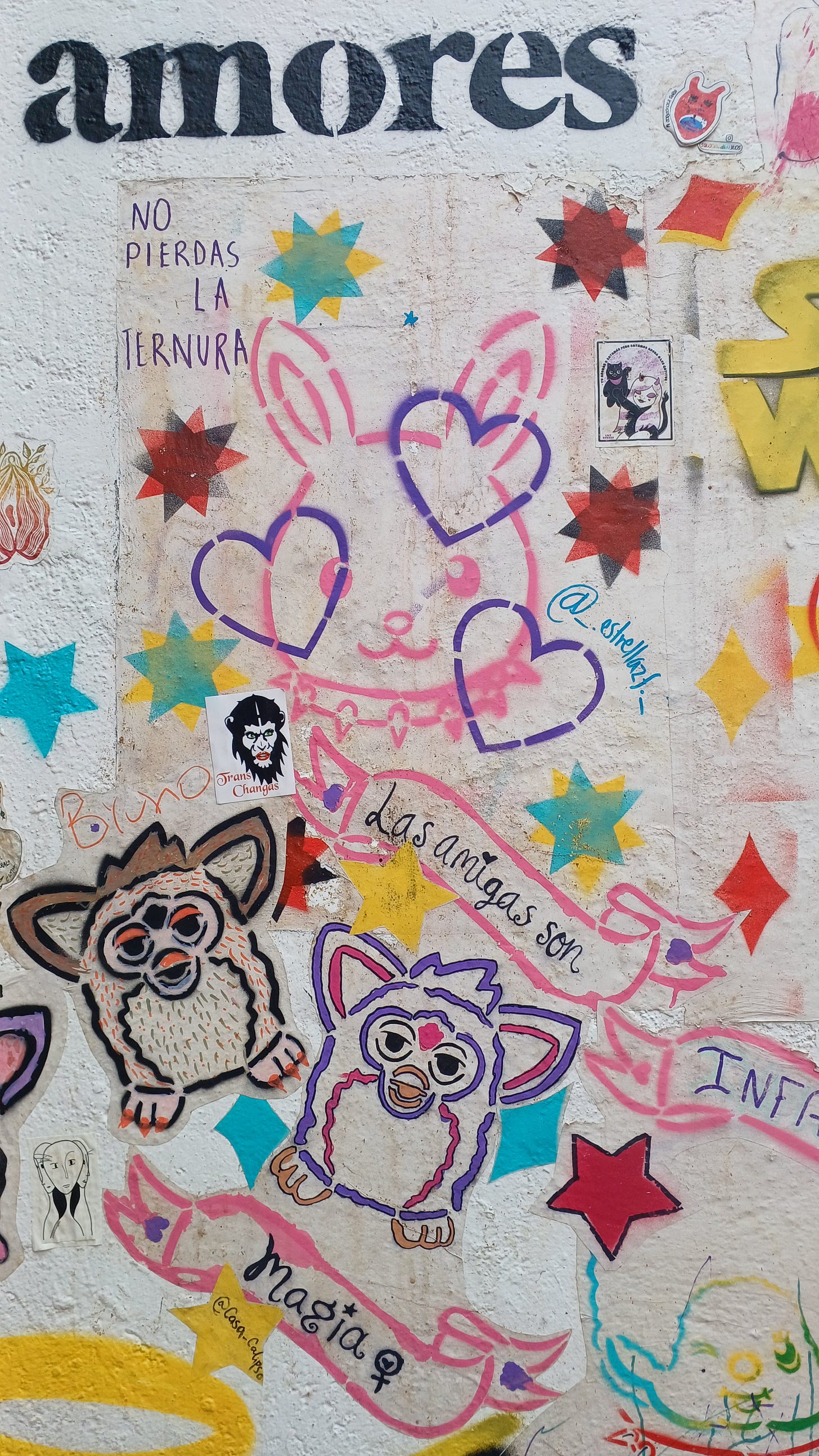 Piccoli murales e stencil nel patio della libreria U-Topicas a Città del Messico: in cima la parola Amor, sotto la scritta “No pierdas la ternura”. Tra un coniglio rosa, immagini stellari e sagome di Gremlins, un'altra scritta dice “Las amigas son magia”.