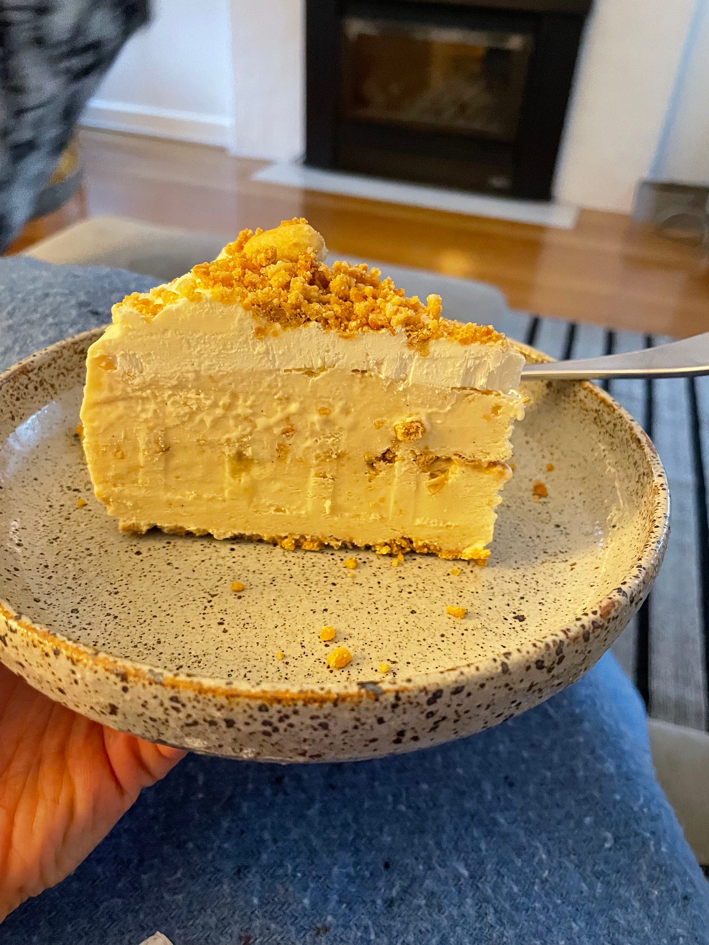 Slice of ice cream cake with a peanut and pretzel crumb, peanut butter and whipped cream, enjoyed on a lounge.