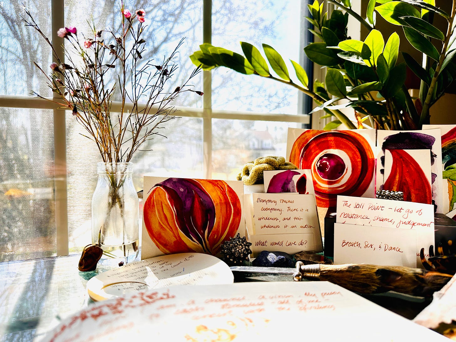 Abstract golden and purple watercolor paintings, piece of paper covered in writing, and a vase of flowers ona. writing desk