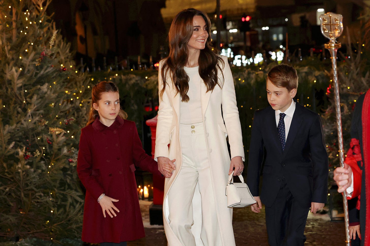 Princess kate in white suit holding hands with Prince George and Princess Charlotte