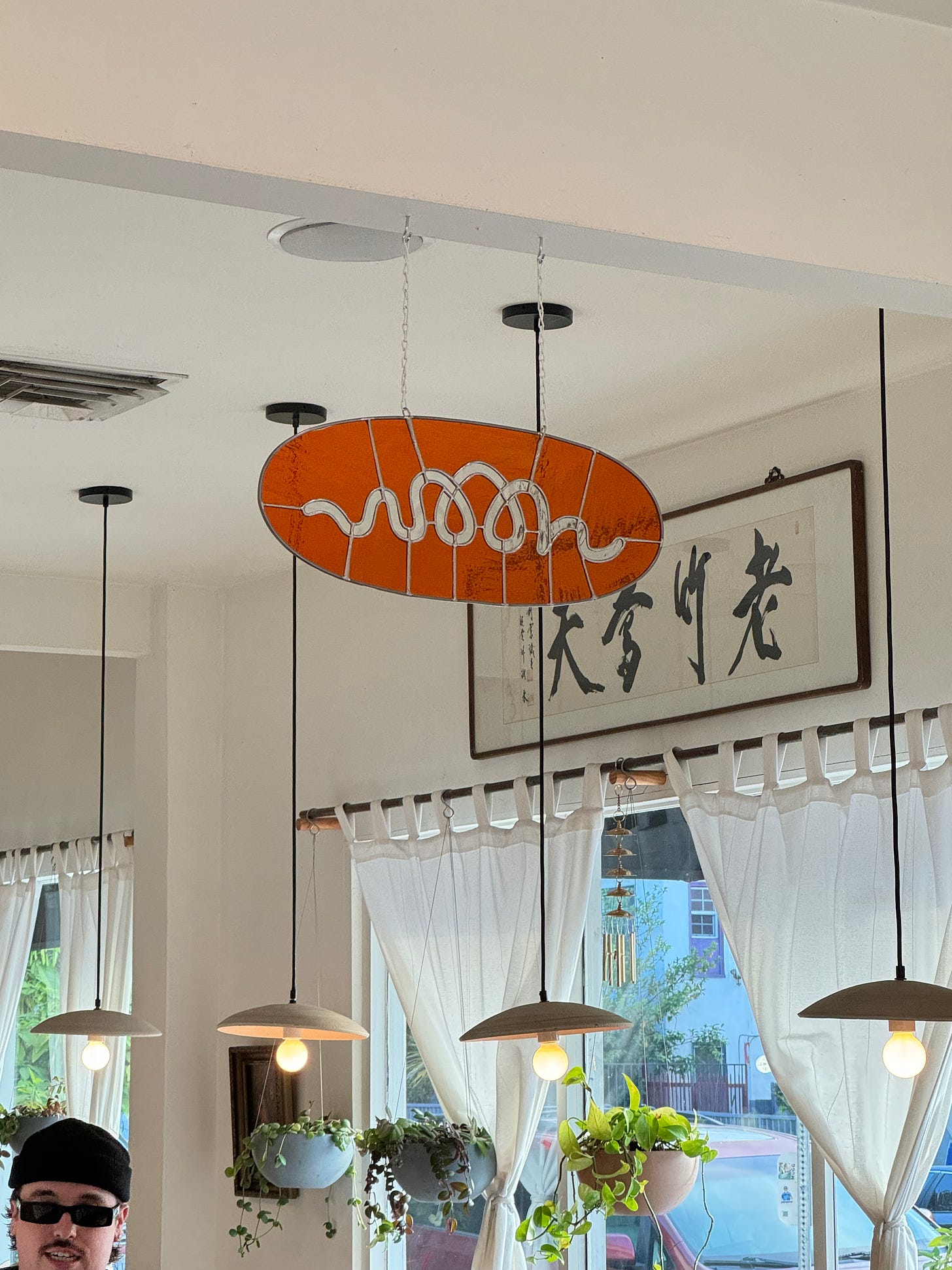 A stained glass Woon logo hanging inside the Woon restaurant.