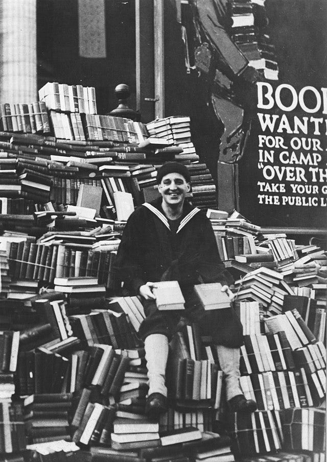 Man sitting on a big pile of books, smiling