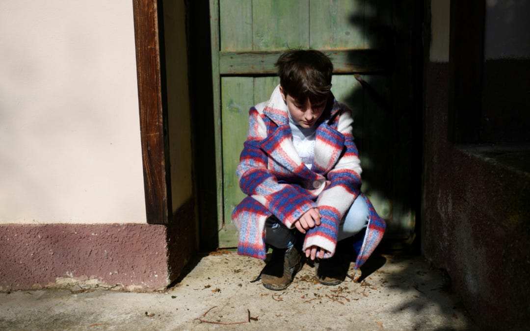 A child crouching in a doorway in the Middle East.