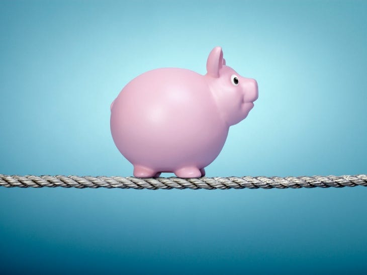 Piggy bank balancing on tightrope