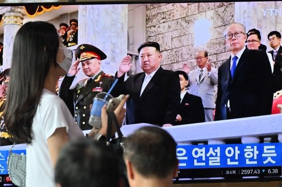 A woman walks past a TV showing a broadcast featuring North Korean leader Kim Jong Un.