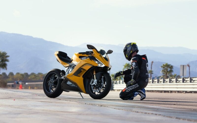 Image of Damon HyperSport Motorcycle and rider kneeling beside it.