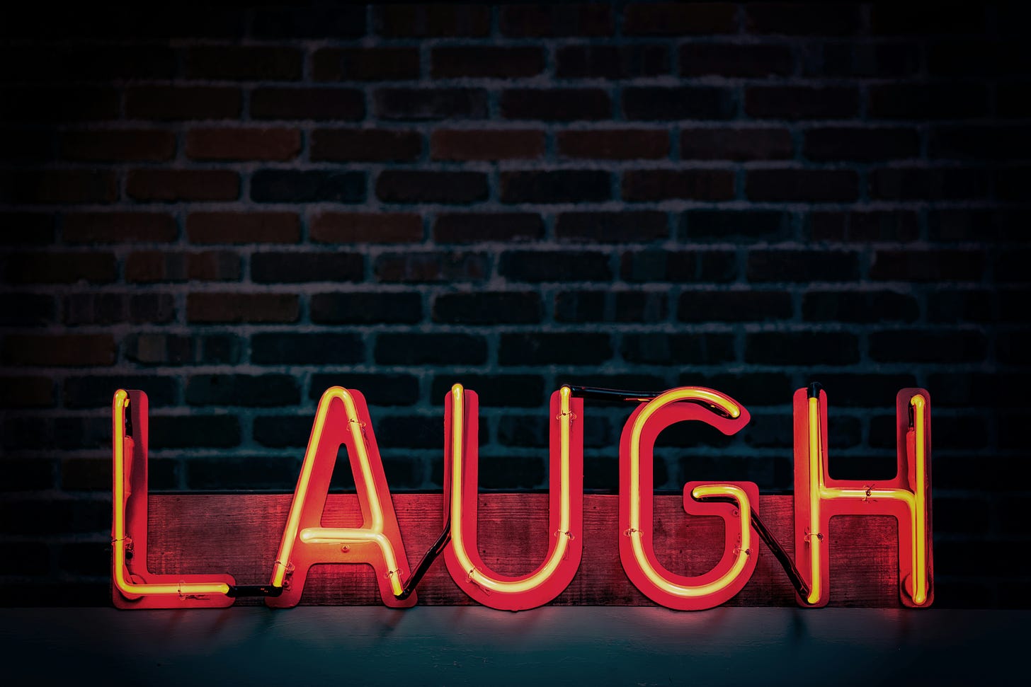 "Laugh" written in orange neon lights in all caps. 