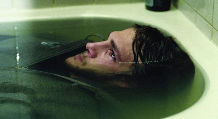 Movie still from The Butterfly Effect. Ashton Kutcher lies in a bathtub that's nearly overflowing, nose and eyes peeking out.