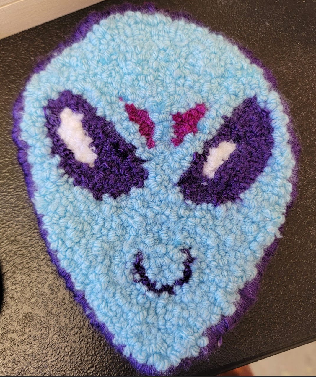 Blue and purple punchneedle alien head mini-rug.