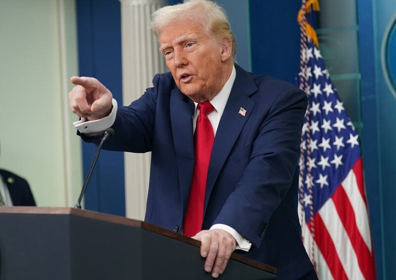 President Donald Trump points from podium with American flag behind him President Donald Trump points from podium with American flag behind him