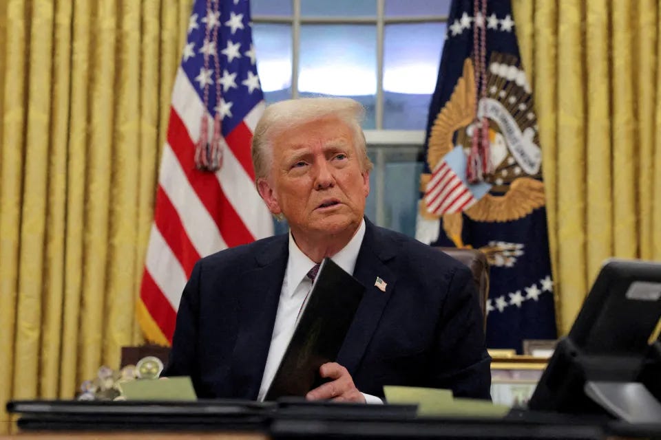 President Trump signing documents in the Oval Office.