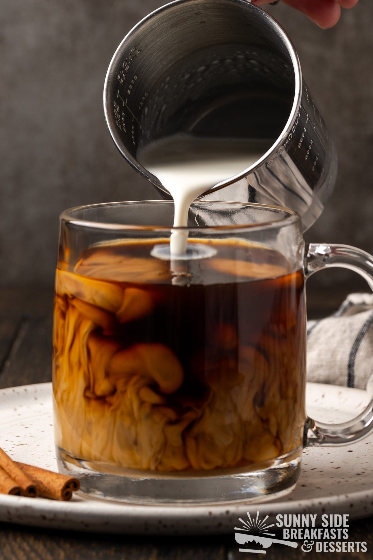 Pouring hot milk into coffee.