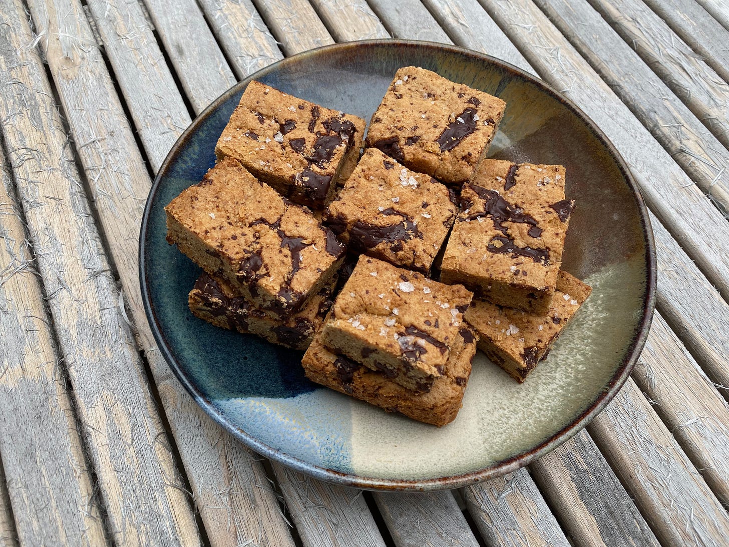 A plate of chocolate tahini bars on a wooden outdoor table.