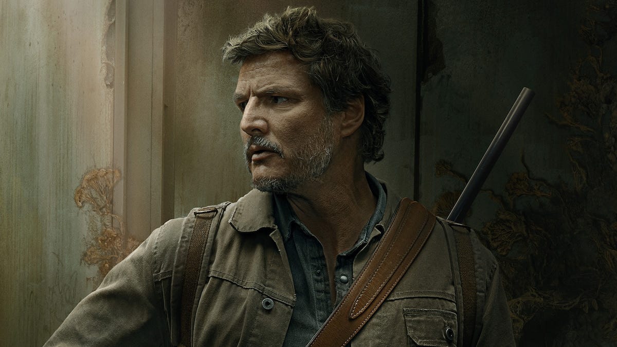 An image of actor Pedro Pascal, a man with grey hair and beard, wearing a brown jacket over a denim shirt with a rifle slung over his shoulder