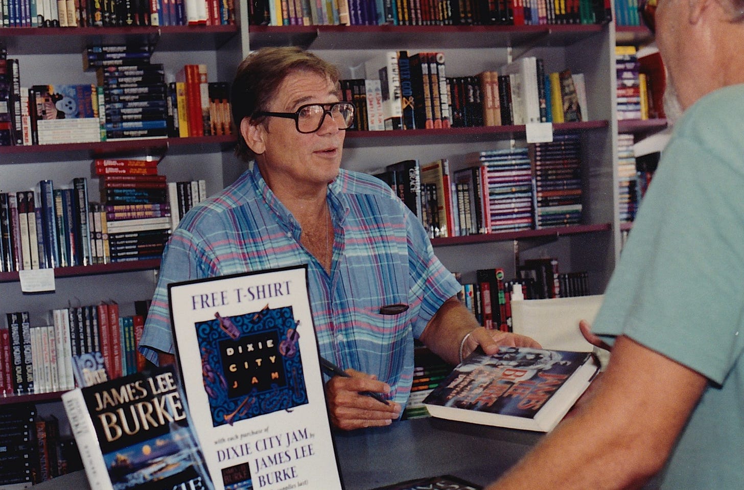 James Lee Burke handing a signed book to a fan.