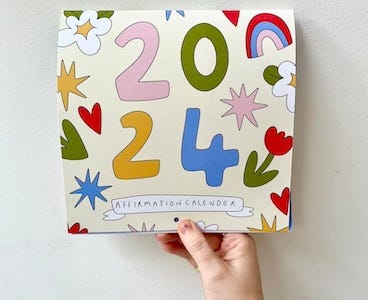 a photo of a hand holding up a 2024 Affirmation Calendar