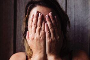 white woman covering face with hands in despair grief discarded america