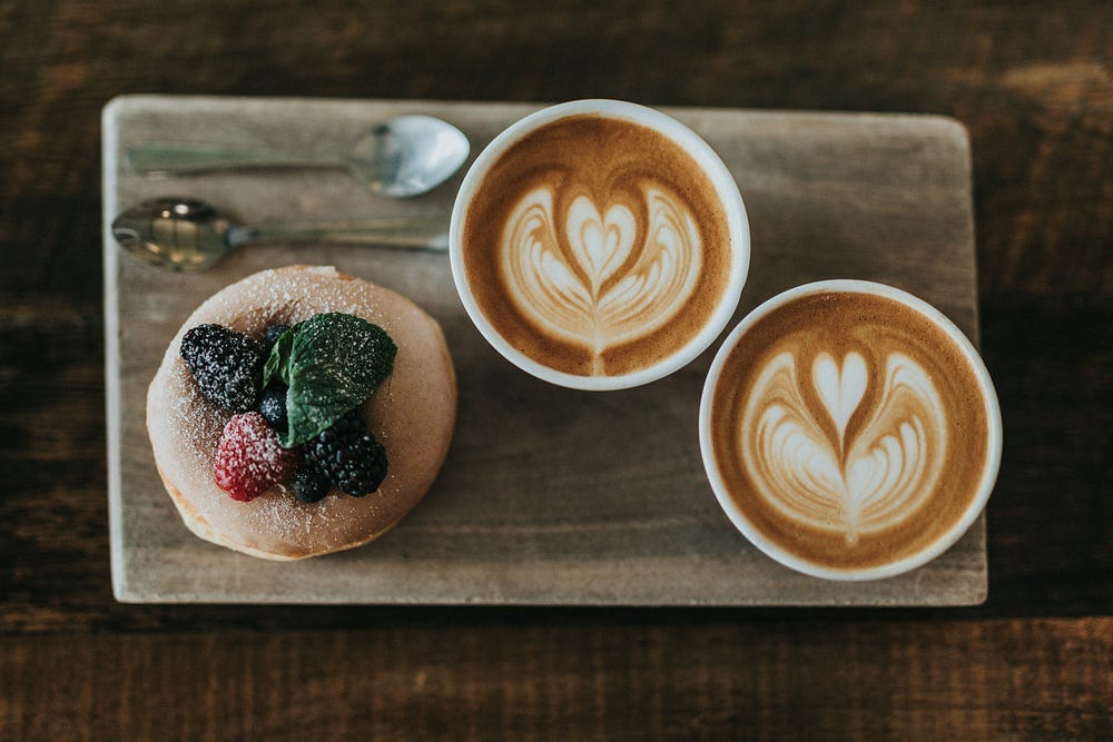 two special coffees with hearts in the foam and a small cake