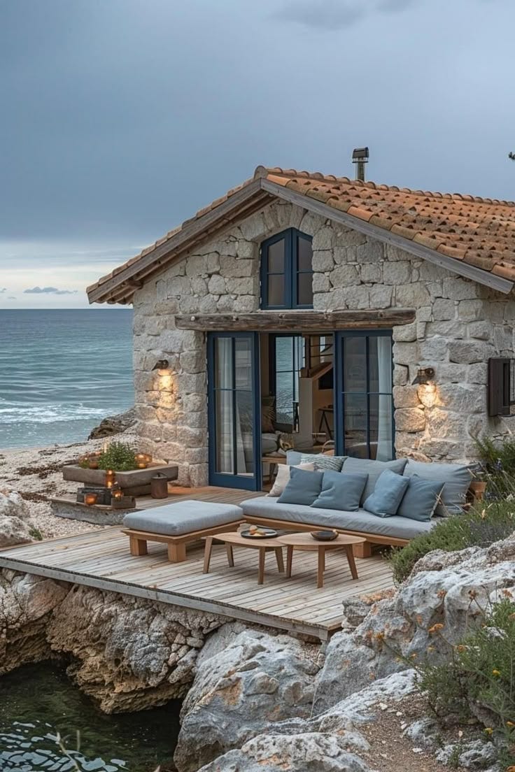This may contain: a stone house sitting on top of a cliff next to the ocean